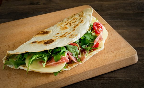 Qual è il modo migliore per preparare una tipica piadina romagnola con stracchino e rucola?